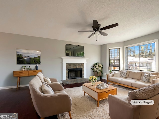 living room featuring ceiling fan, wood-type flooring, a fireplace, and a textured ceiling