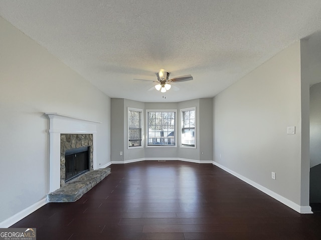 unfurnished living room with dark hardwood / wood-style flooring, a textured ceiling, a fireplace, and ceiling fan