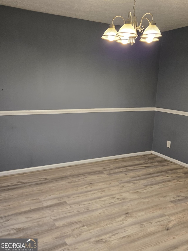 unfurnished room featuring hardwood / wood-style flooring and a chandelier