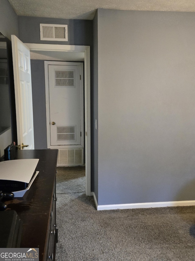 hallway featuring carpet flooring and a textured ceiling