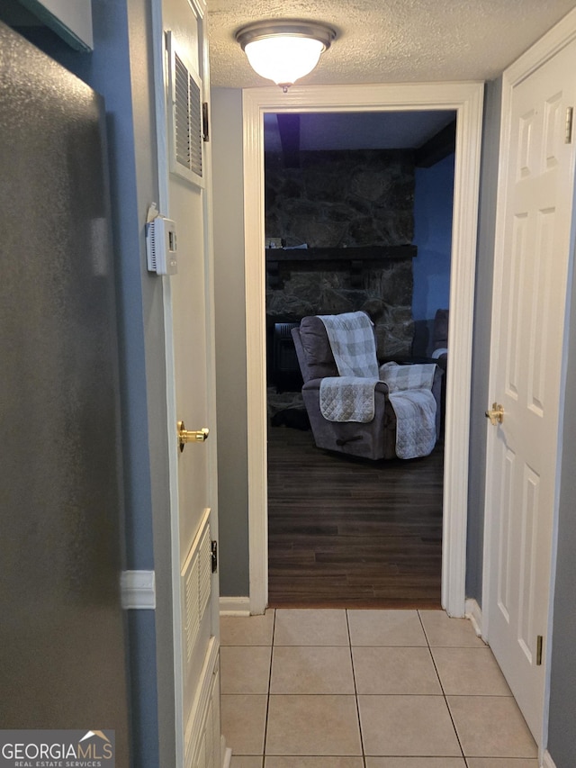 hall featuring light tile patterned floors and a textured ceiling