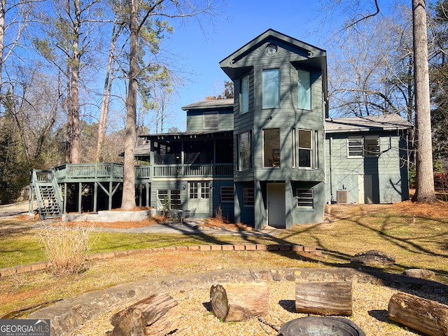 back of property featuring a yard, a sunroom, and a deck