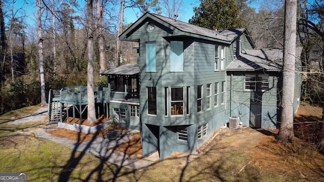 rear view of property featuring a deck, a sunroom, and central air condition unit