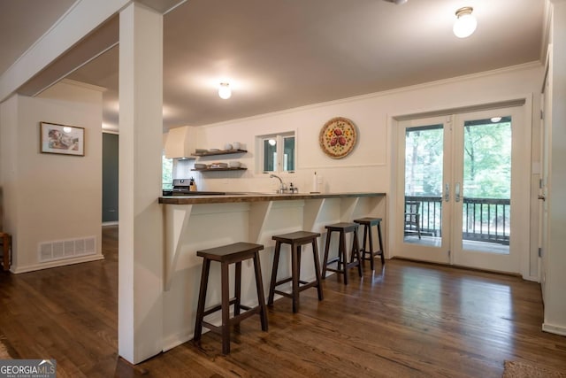 kitchen featuring dark hardwood / wood-style floors, a kitchen breakfast bar, kitchen peninsula, and white cabinets