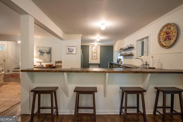 kitchen featuring sink, dark wood-type flooring, a breakfast bar area, white cabinets, and kitchen peninsula