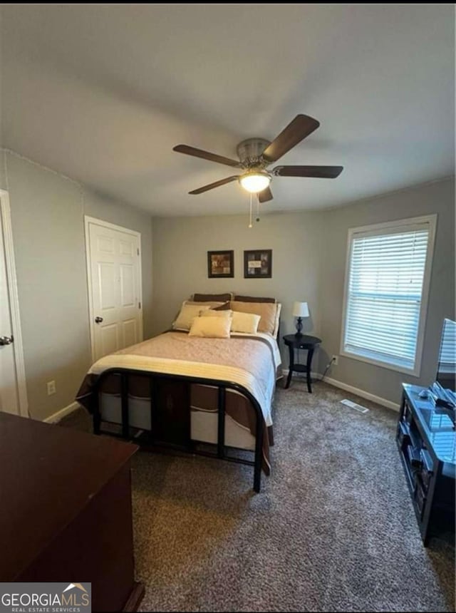 bedroom featuring ceiling fan, dark carpet, and a closet