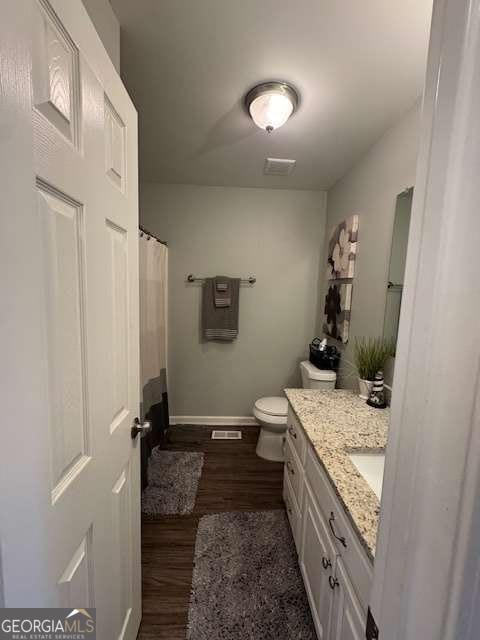 bathroom featuring vanity, wood-type flooring, and toilet