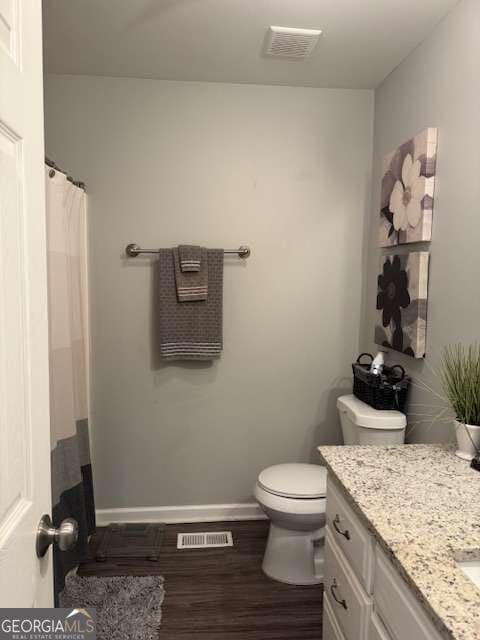 bathroom featuring vanity, toilet, and hardwood / wood-style floors