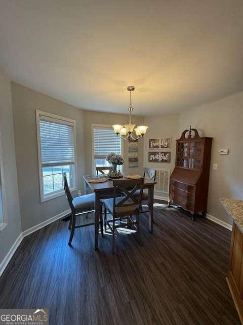 dining room featuring dark hardwood / wood-style flooring and an inviting chandelier