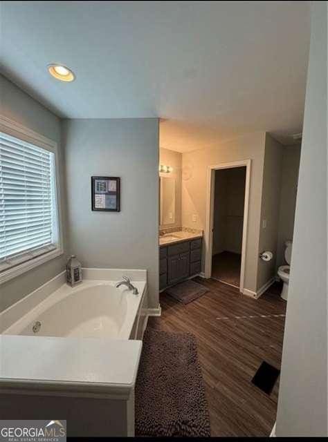 bathroom featuring hardwood / wood-style flooring, vanity, toilet, and a tub