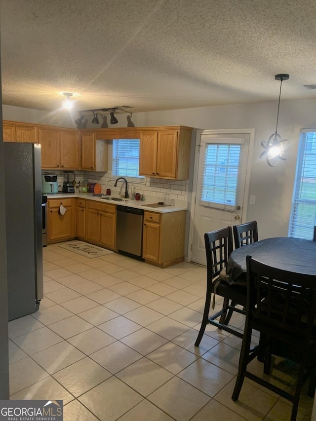 kitchen with pendant lighting, light tile patterned floors, sink, appliances with stainless steel finishes, and tasteful backsplash