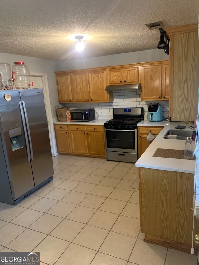 kitchen with tasteful backsplash, appliances with stainless steel finishes, light tile patterned floors, and a textured ceiling