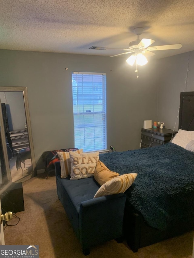 bedroom with a textured ceiling, ceiling fan, and carpet flooring