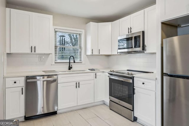 kitchen with white cabinetry, stainless steel appliances, sink, and backsplash