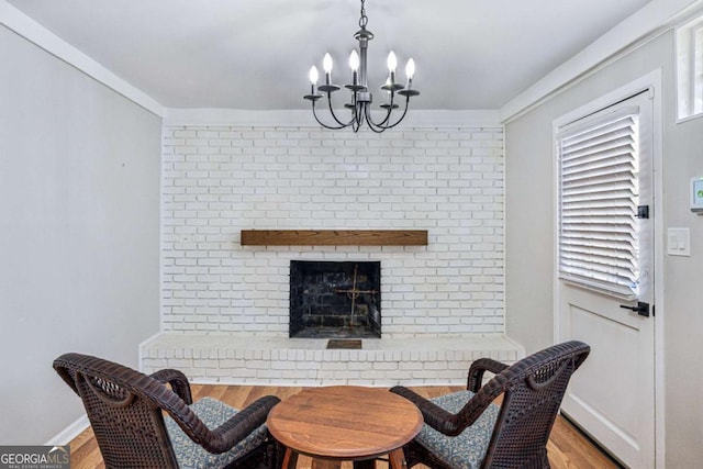 dining room with a brick fireplace, a chandelier, and light wood-type flooring