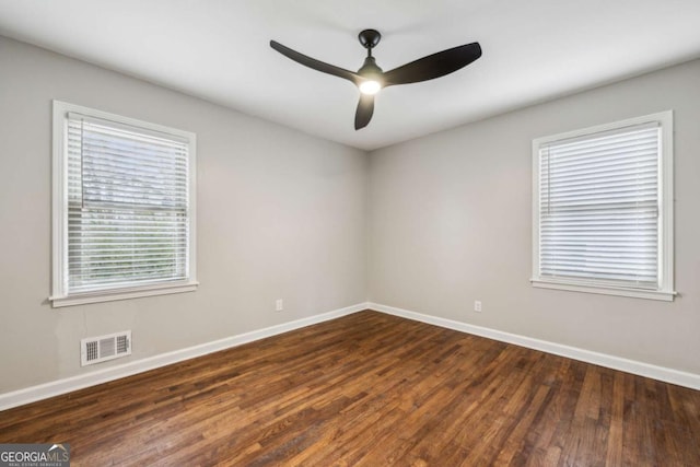 empty room with plenty of natural light, dark hardwood / wood-style floors, and ceiling fan