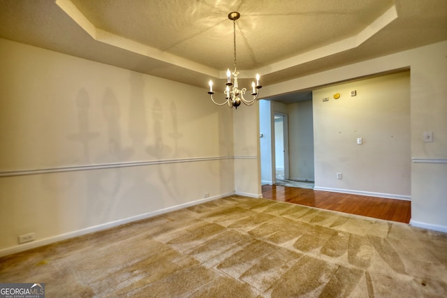 spare room with an inviting chandelier and a raised ceiling