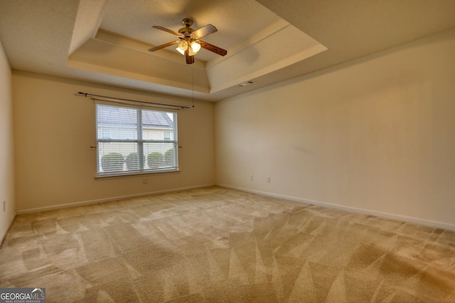 carpeted empty room featuring ceiling fan and a tray ceiling