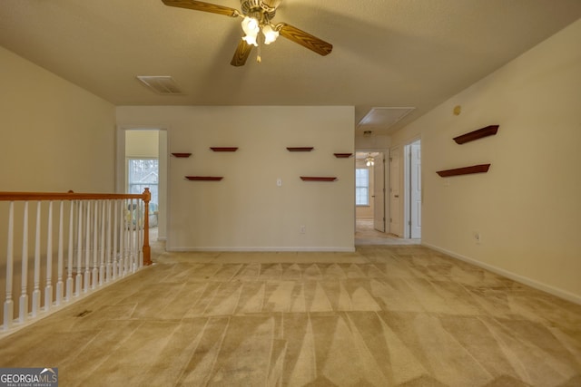 spare room featuring ceiling fan, light carpet, and a textured ceiling