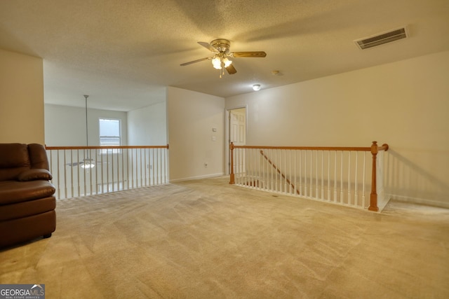 empty room with ceiling fan, carpet flooring, and a textured ceiling