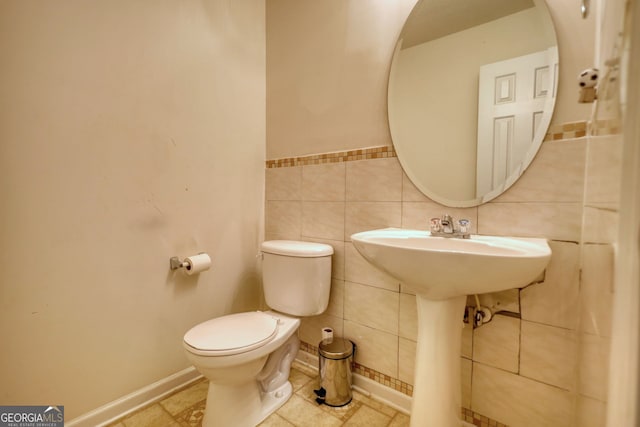 bathroom featuring tile walls and toilet