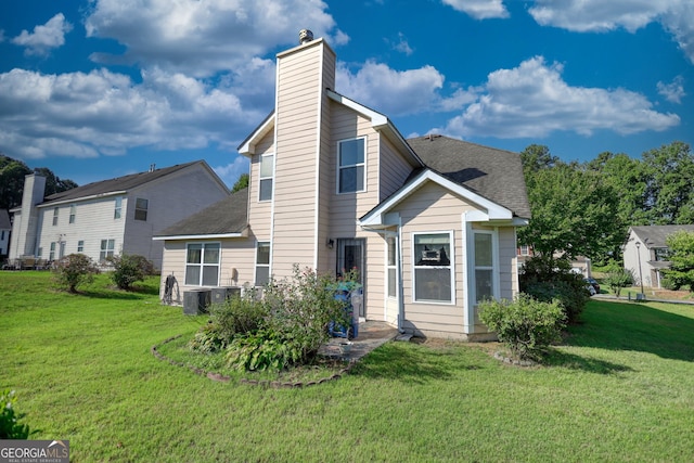 rear view of house featuring a lawn and central air condition unit