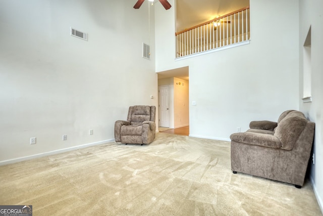 sitting room with a towering ceiling, ceiling fan, and carpet flooring