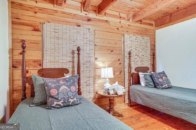 bedroom with hardwood / wood-style floors, beam ceiling, wooden walls, and wooden ceiling