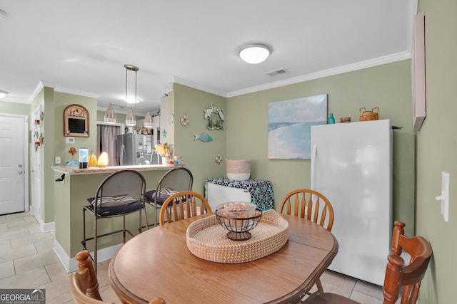 dining area featuring ornamental molding and light tile patterned flooring