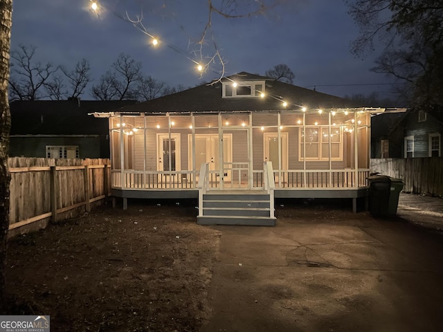 back house at twilight featuring covered porch and a patio area