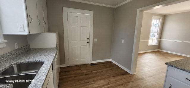 kitchen with dark wood-type flooring, sink, white cabinetry, crown molding, and light stone countertops