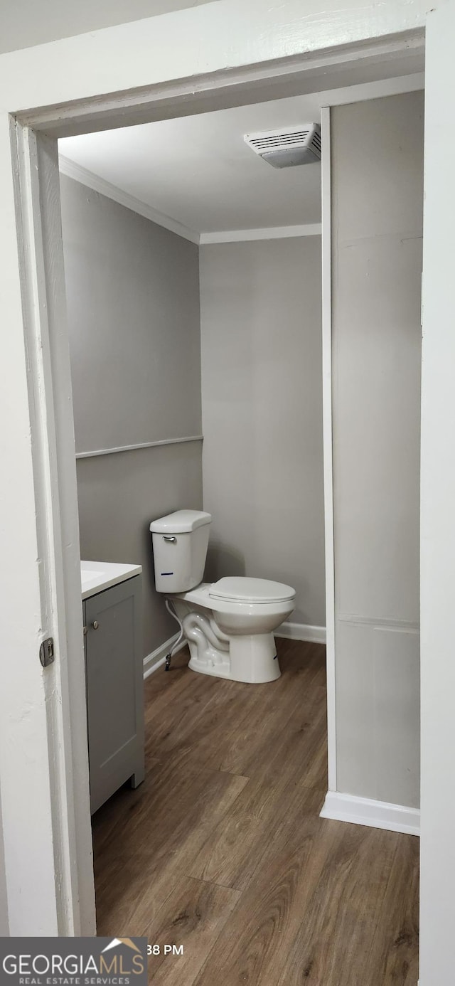 bathroom featuring ornamental molding, wood-type flooring, toilet, and vanity