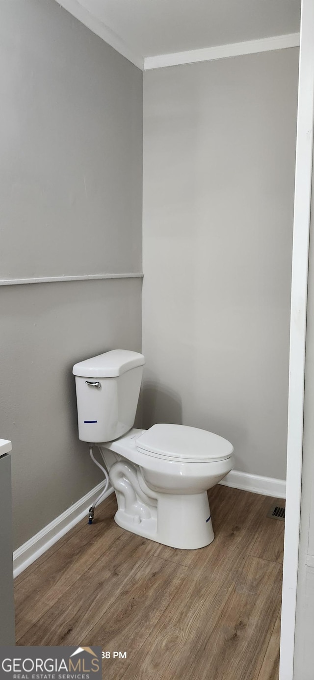 bathroom featuring crown molding, wood-type flooring, and toilet