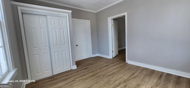 unfurnished bedroom featuring hardwood / wood-style floors, crown molding, and a closet