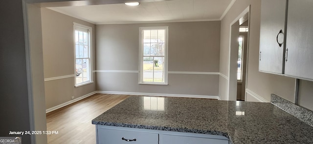 kitchen with crown molding, wood-type flooring, a wealth of natural light, and dark stone counters