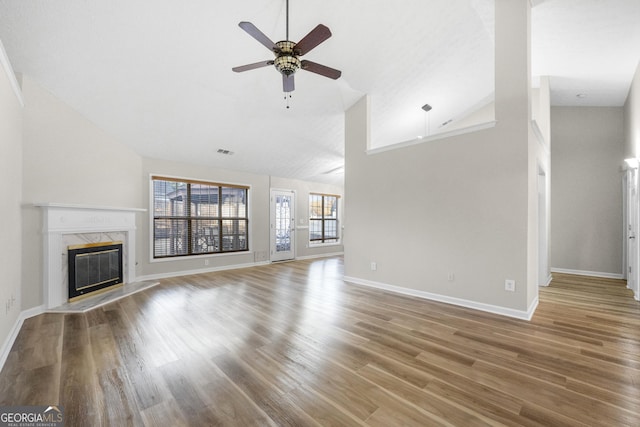 unfurnished living room featuring ceiling fan, a high end fireplace, high vaulted ceiling, and wood-type flooring