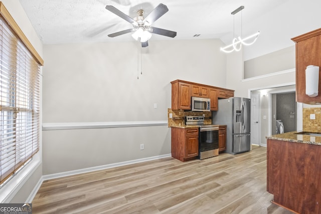 kitchen featuring light wood-style flooring, appliances with stainless steel finishes, brown cabinets, decorative light fixtures, and light stone countertops