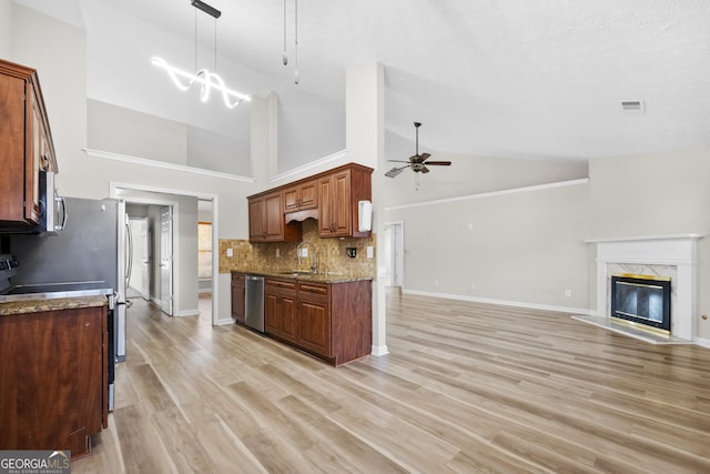 kitchen featuring stainless steel appliances, a fireplace, a sink, a ceiling fan, and open floor plan