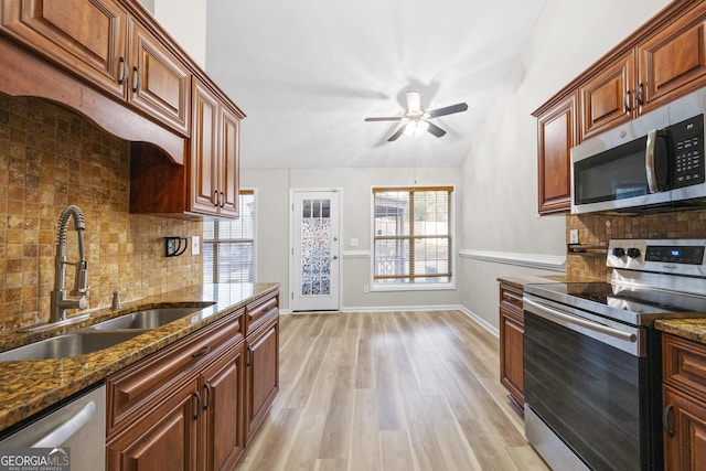 kitchen featuring stainless steel appliances, light wood finished floors, a sink, and a healthy amount of sunlight