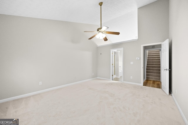 unfurnished bedroom featuring high vaulted ceiling, carpet flooring, baseboards, and a ceiling fan