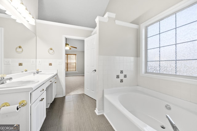 bathroom featuring tile walls, vanity, ornamental molding, ceiling fan, and a bath