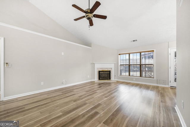 unfurnished living room featuring hardwood / wood-style flooring, ceiling fan, lofted ceiling, and a high end fireplace