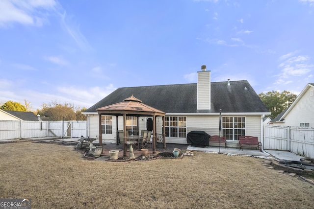 back of house featuring a fenced backyard, a gazebo, a yard, a chimney, and a patio area