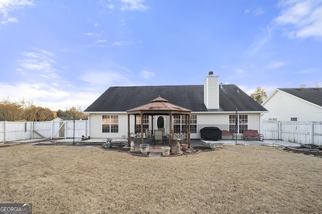 rear view of house with a gazebo, a patio area, a fenced backyard, and a gate