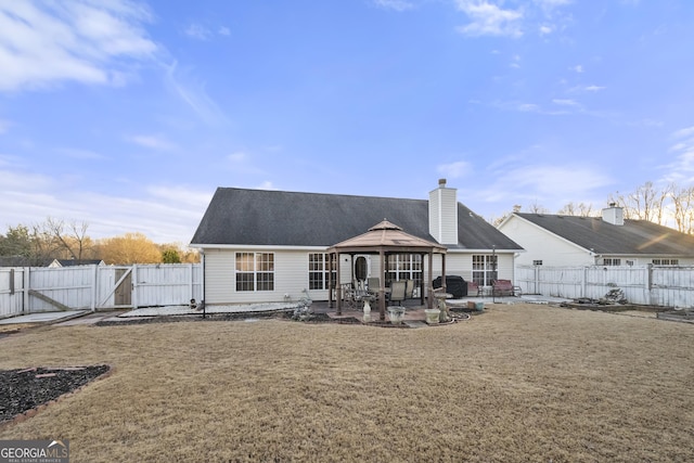 rear view of property with a gazebo, a patio area, and a lawn