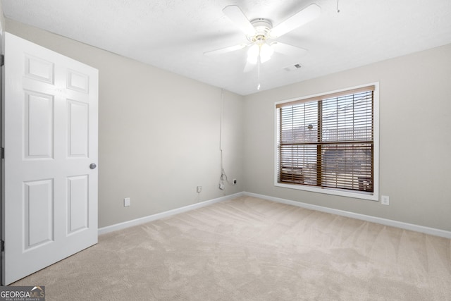 empty room featuring visible vents, ceiling fan, light carpet, and baseboards