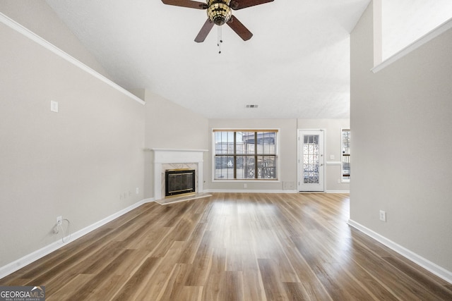 unfurnished living room featuring a fireplace, lofted ceiling, visible vents, wood finished floors, and baseboards