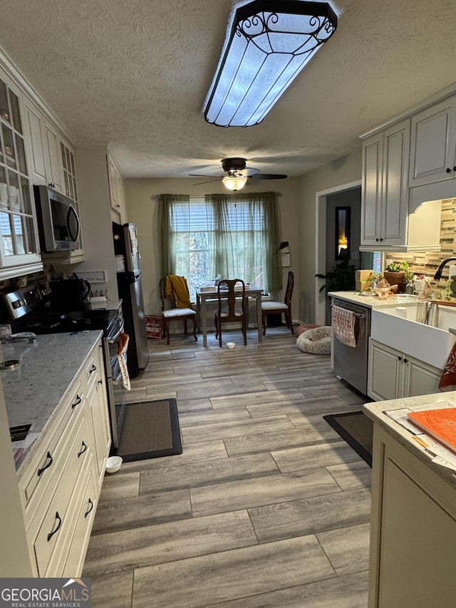 kitchen featuring glass insert cabinets, stainless steel appliances, light wood finished floors, and white cabinetry