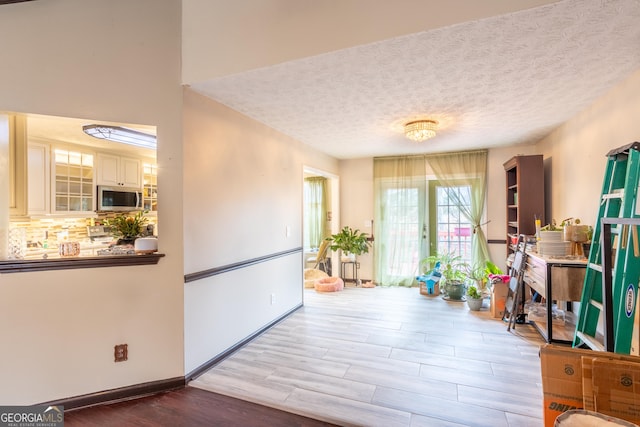 interior space featuring a textured ceiling, light wood finished floors, and baseboards