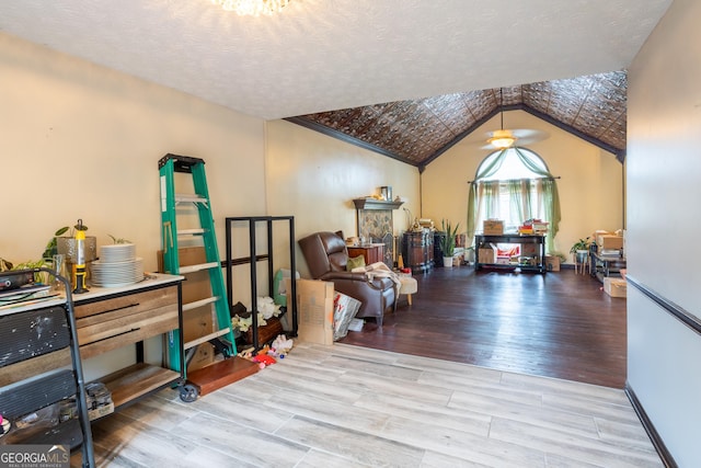 interior space featuring a textured ceiling, light wood finished floors, and lofted ceiling